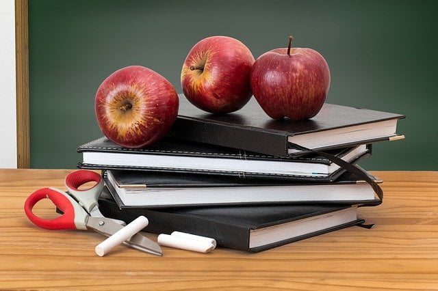 Apples on top of books on a desk